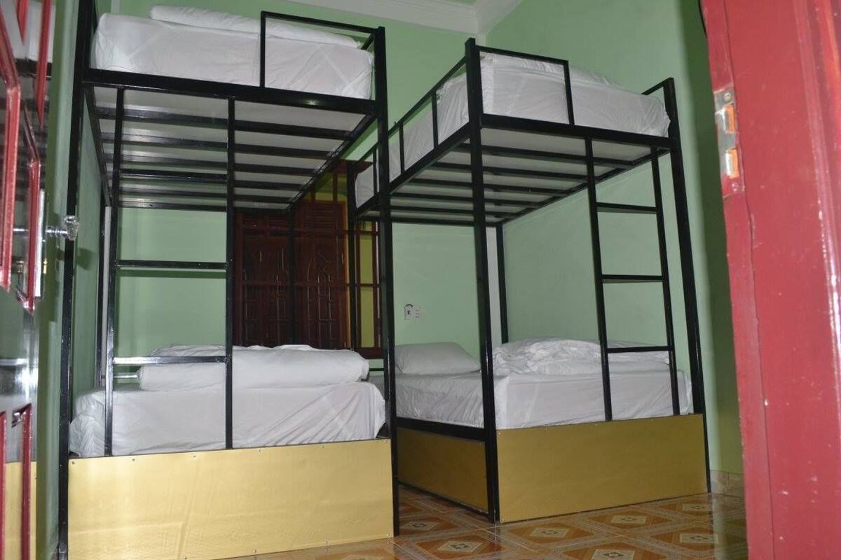 A room with bunk beds, green walls, and a tiled floor.