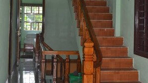 Una escalera de madera con barandilla que lleva a un rellano con una mesa y sillas.