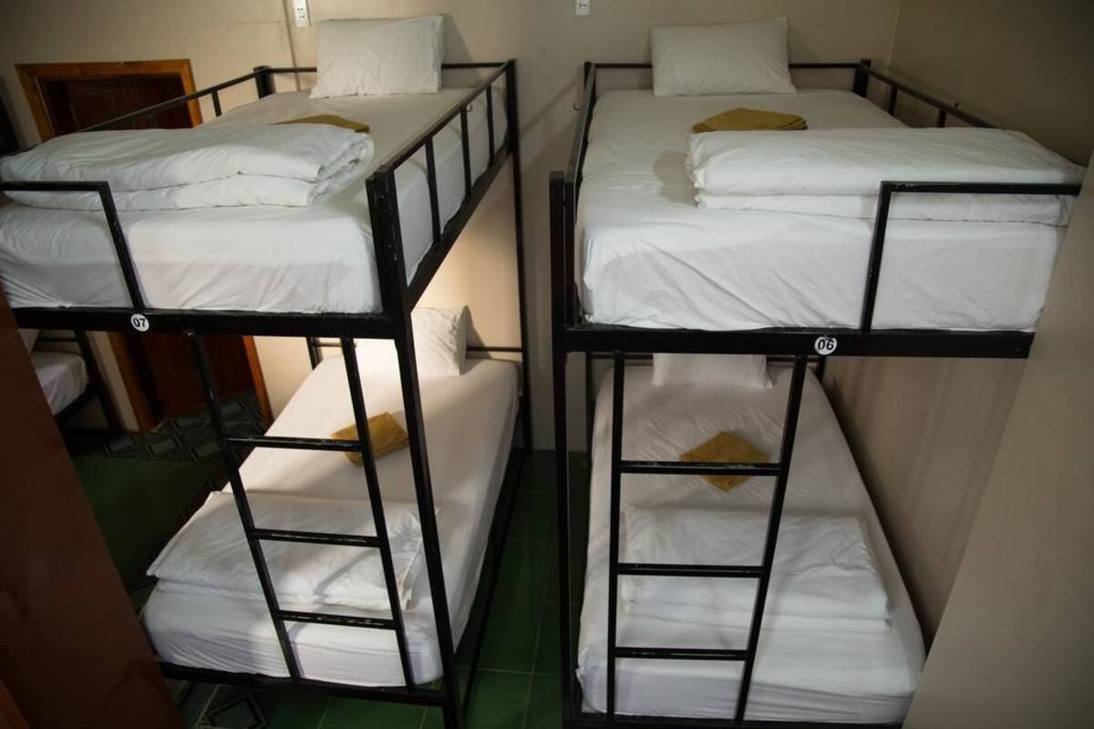 Bunk beds with white bedding and a yellow pillow.