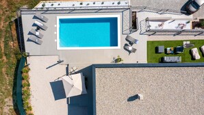 Vista aérea de una azotea con piscina, mobiliario exterior y un coche aparcado cerca.