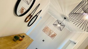 Un interior moderno con una mesa de comedor de madera, espejos en la pared y lámparas de techo con formas geométricas.