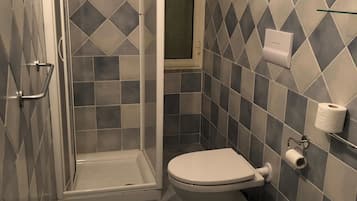 A bathroom with a shower, toilet, and sink, featuring a geometric tile pattern on the walls and floor.