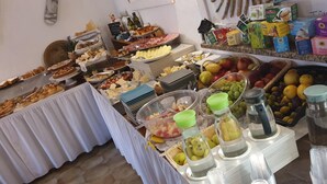 Un buffet proposant une variété de plats, notamment des fruits, des fromages et des pâtisseries.