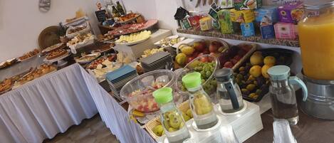 Un bufé con diversas opciones de comida, como frutas, quesos y pasteles.