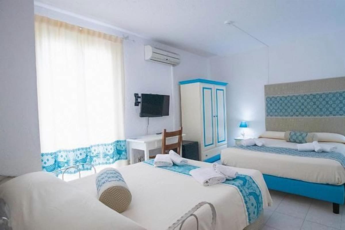 A hotel room with two beds, a desk, a TV, and a wardrobe.