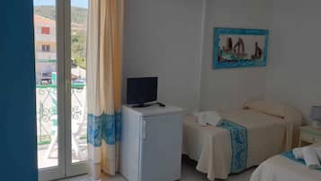 Quarto de hotel com duas camas, uma televisão pequena em uma mesa e um quadro na parede.