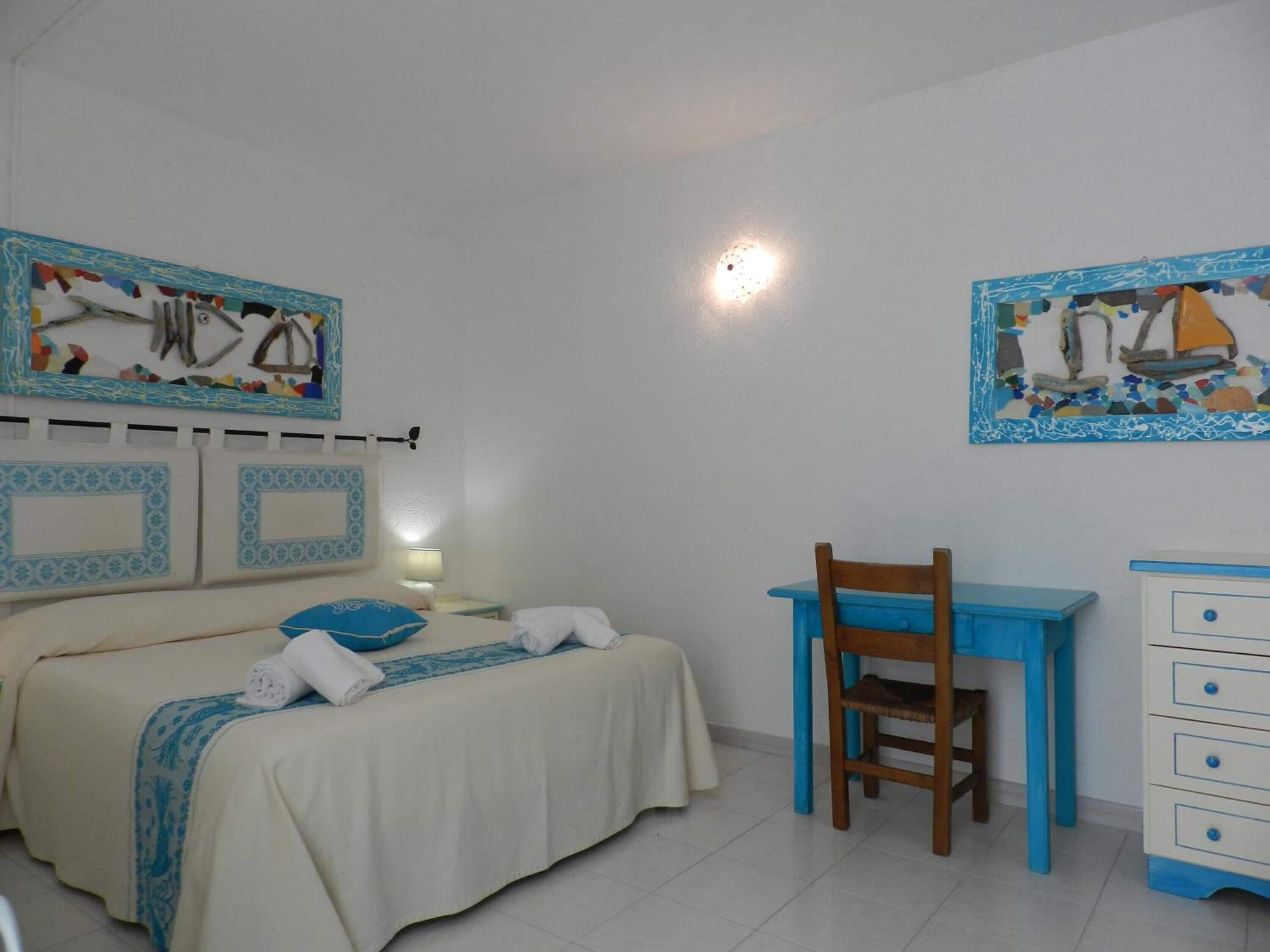 Un dormitorio con cama, escritorio, silla y cómoda.