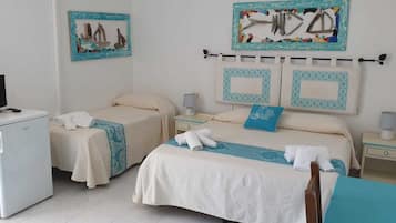 Quarto de hotel com duas camas, televisão, frigorífico e obras de arte nas paredes.