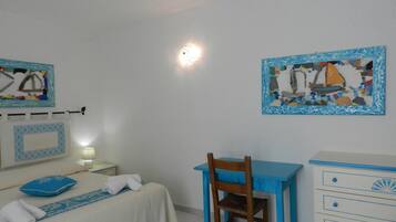 Een slaapkamer met een bed, een bureau en een stoel. Twee schilderijen hangen aan de muur.