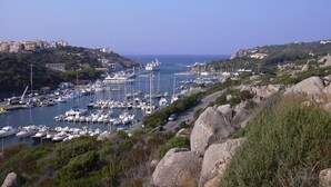 Un port de plaisance situé sur la côte, avec des bateaux amarr és, entouré d’un paysage rocheux et de bâtiments.