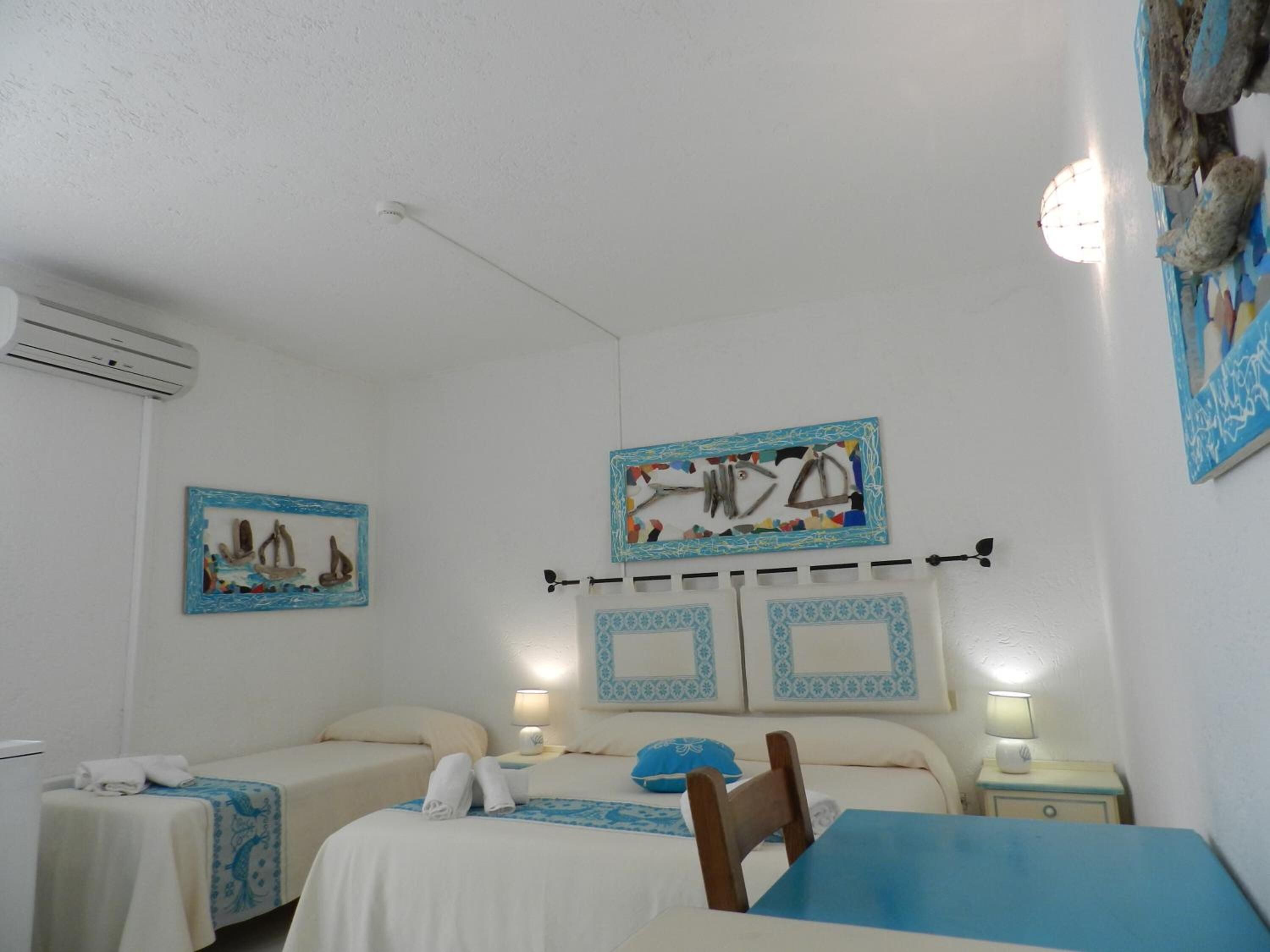 Een hotelkamer met twee bedden, een tafel en kunstwerken aan de muren.