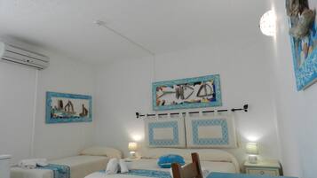 Een hotelkamer met twee bedden, een tafel en kunstwerken aan de muren.