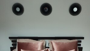 Ein ordentlich bezogenes Bett mit Kissen und Decke, eine Wandleuchte und eine Wand mit Muster.