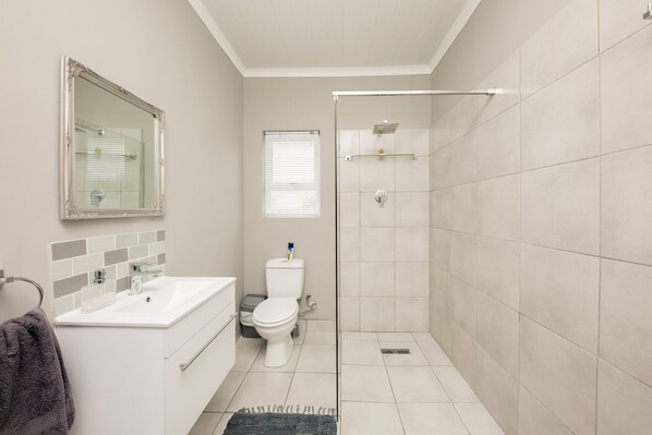 A bathroom with a white sink, toilet, and shower. - Villa Eika (Grabouw)