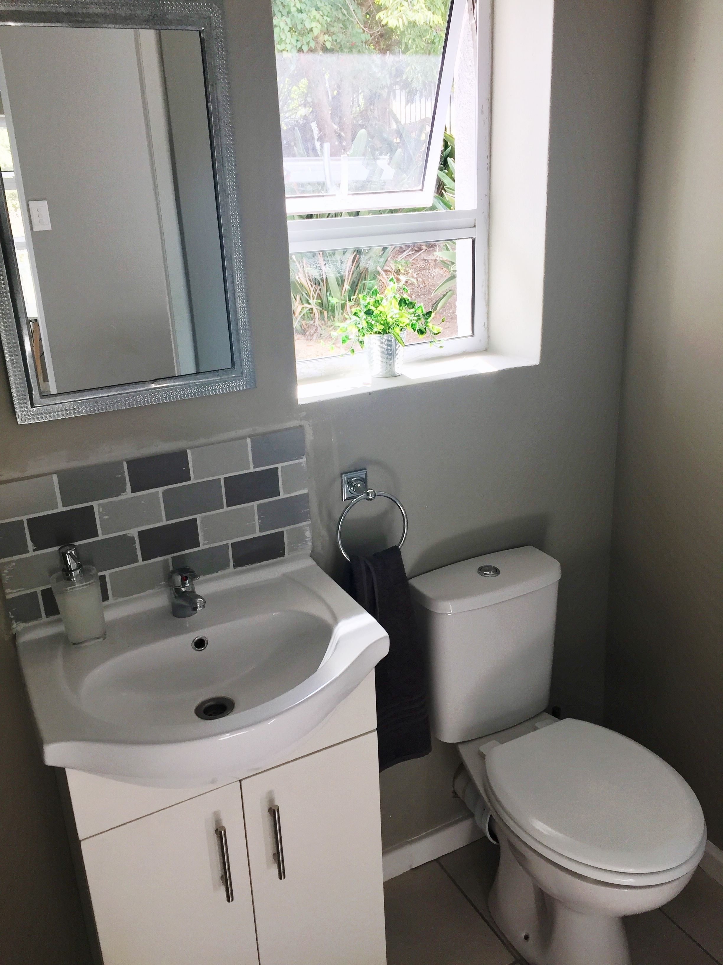 A bathroom with a white sink, mirror, and toilet.