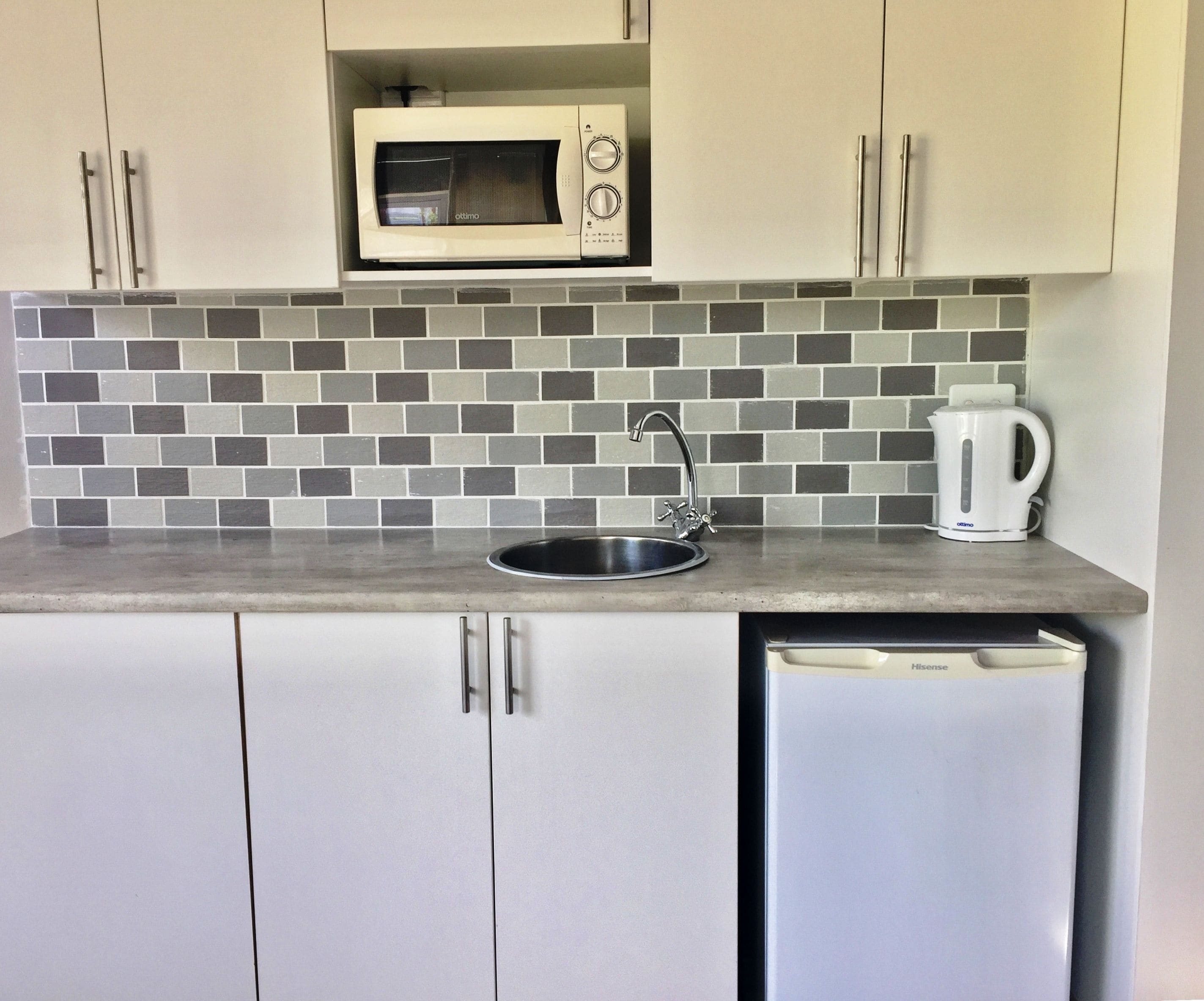 A kitchenette with a microwave, sink, and coffee maker.