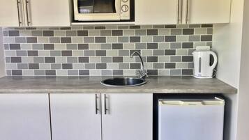A kitchenette with a microwave, sink, and coffee maker.