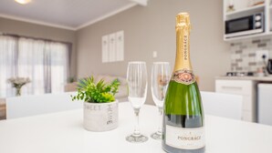 A bottle of PONGRACZ champagne, two empty glasses, and a potted plant on a white table in a modern kitchen setting.