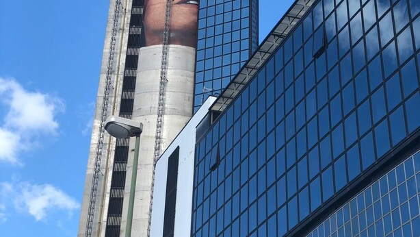 Un bâtiment moderne doté d’une grande structure cylindrique ornée d’une fresque murale.