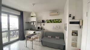 Un appartement moderne comprenant un coin repas, une kitchenette et un salon avec un canapé.