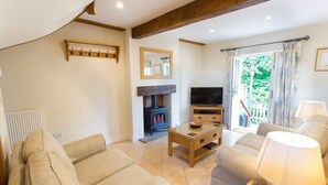 A cozy living room with a fireplace, a television, and comfortable seating. - The Stables at Boreham House (Hailsham)