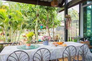 Een eettafel met stoelen, een glazen tafel en een kamerplant.