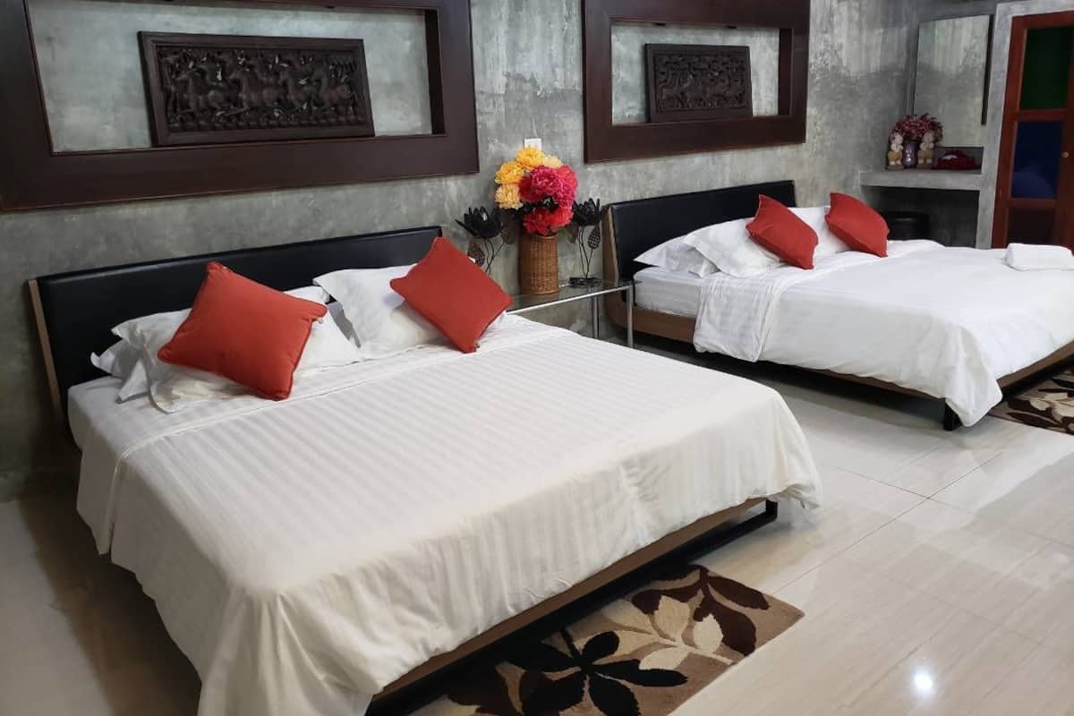 A hotel room with two beds, each with white bedding and red pillows, a vase of flowers, and artwork on the walls.