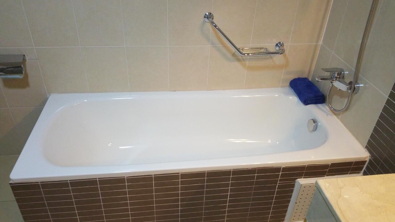 A standard bathroom with a bathtub, a shower, and a grab bar.