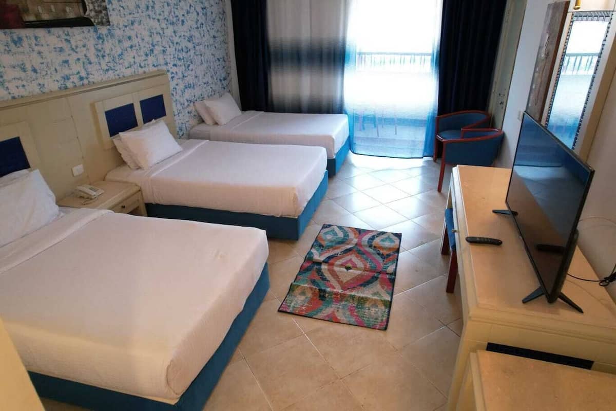 Ein Hotelzimmer mit zwei Betten, einem Fernseher und einem Balkon mit Blick.