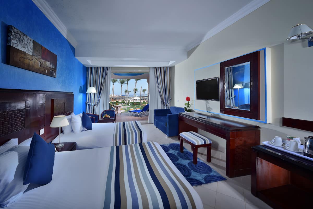 Ein Hotelzimmer mit zwei Betten, einem Schreibtisch, einem Fernseher und Blick ins Freie.