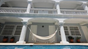 Un área de piscina con una hamaca, columnas blancas y plantas en macetas.