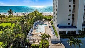 Un hôtel doté d’une piscine, offrant une vue sur la plage et bordé de palmiers.