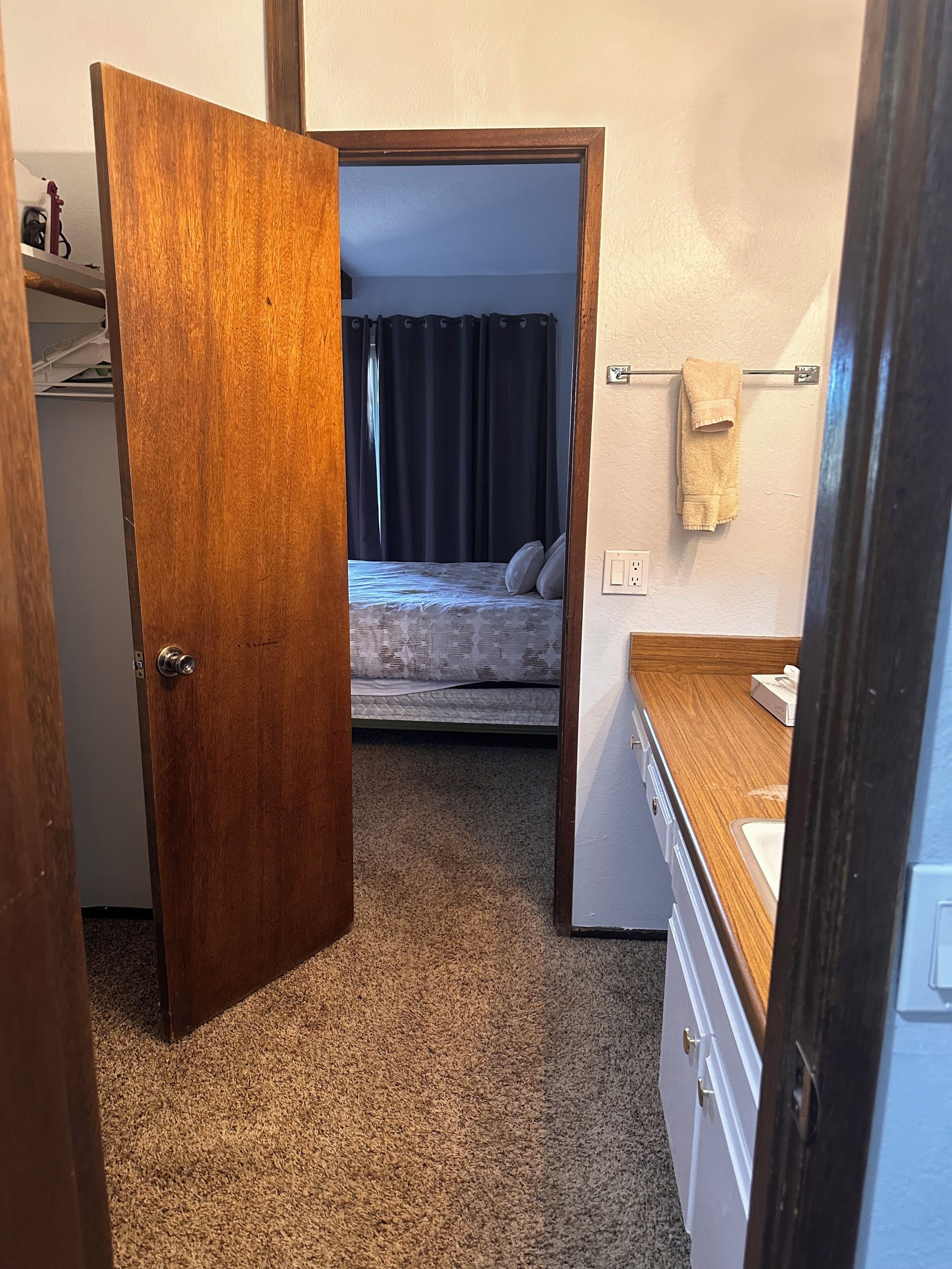 A bedroom with a bed, a nightstand, and a window with curtains.