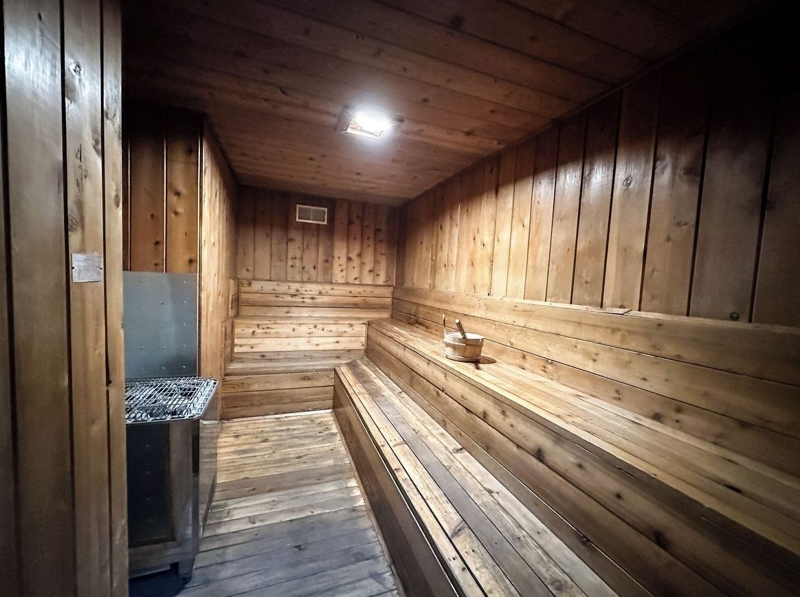 Et træsauna-rum med bænke og ovn.