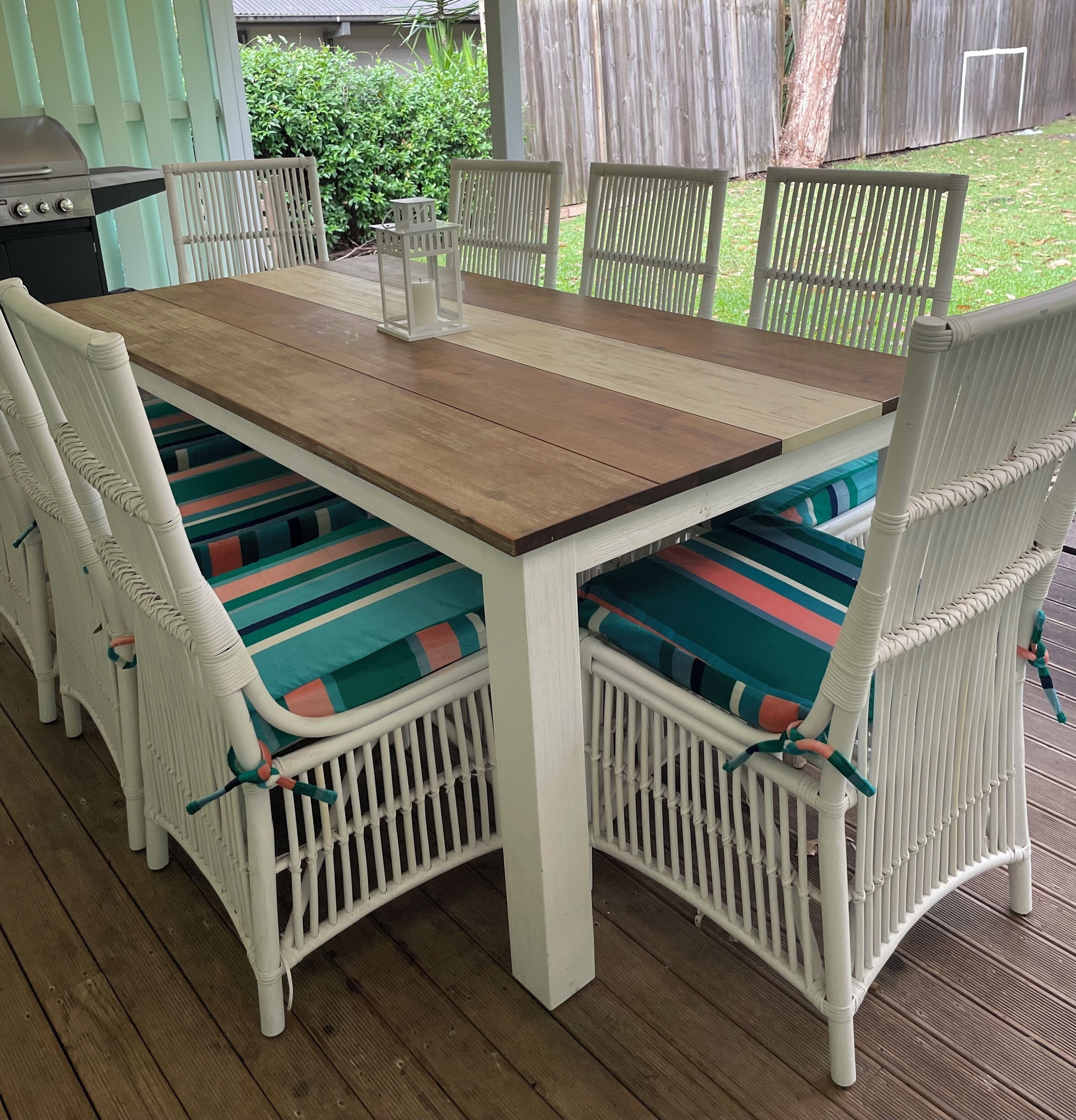Una mesa de madera con sillas blancas, cada una con un cojín de colores.