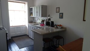 Una cocina con un lavamanos, encimera y una ventana. Hay armarios, un tostador y un cuenco con fruta sobre la encimera.
