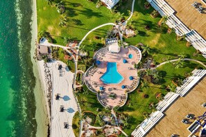 An aerial view of a resort with a central pool, beach access, and landscaped areas. - St. Pete Isla Bahia Vista 12-343: 2BD/2BA (Isla Del Sol)