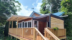 Une cabane en bois dotée d’une terrasse, d’un porche couvert et d’un toit bleu.