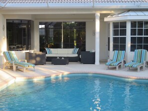 Relax by the serene pool surrounded by comfortable lounge seating and a shaded pergola.