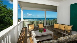 A covered outdoor seating area with wicker furniture and a view of the ocean. - Luxuriously Restored Historic Hilltop Estate with Harbor & Ocean views (Governors Harbour)