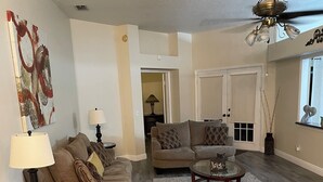A spacious living room with a wooden floor, two sofas, a coffee table, and a chandelier. - Spacious & amazing lake view with pool.  (Brandon)