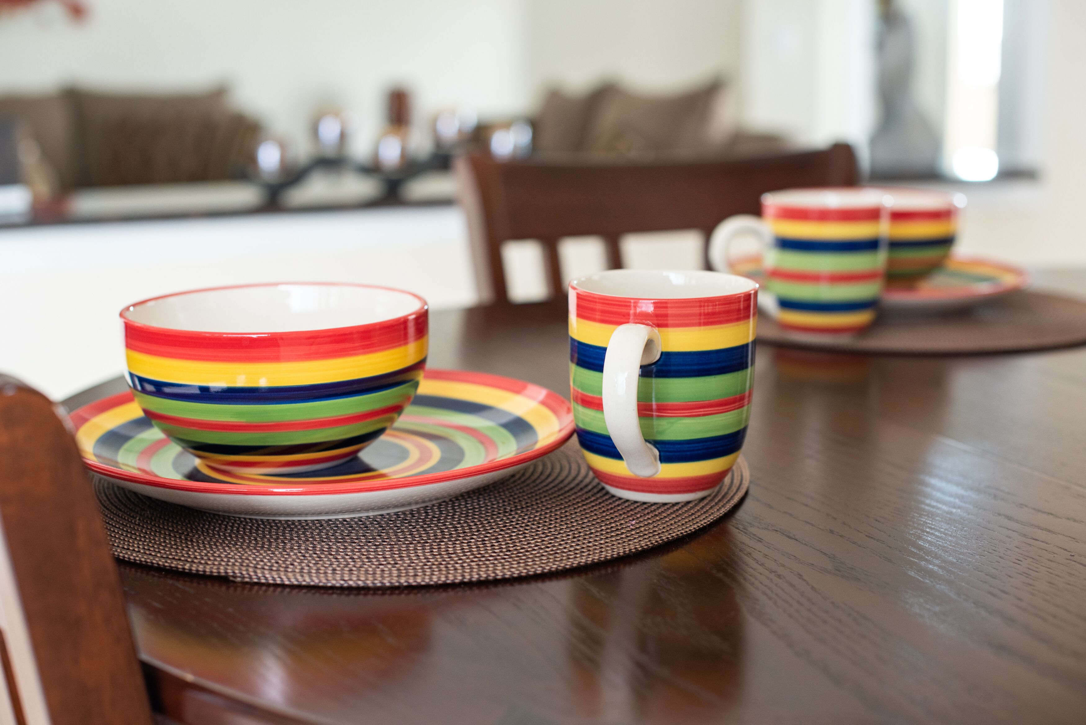 A dining table with colorful striped bowls and plates.