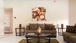 A living room with a brown sofa, a glass coffee table, and a patterned rug. - Spacious & amazing lake view with pool.  (Brandon)