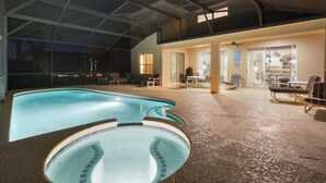 Una piscina interior con una zona hundida, rodeada de sillones y mesas, bajo un techo de vidrio.