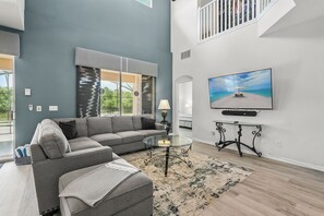 Relax in a stylish living room with a large sofa, flat-screen TV, and a view of the outdoors.