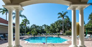 Relax by the serene pool surrounded by lush greenery and palm trees.