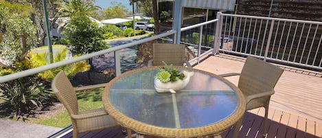 A balcony with wicker furniture, a glass table, and a decorative whale bowl.