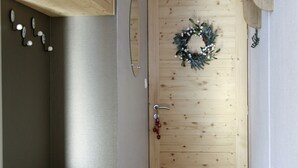 Eine Holztür mit einem Kranz, eine Holzbank und ein an der Wand befestigter Kleiderhaken.