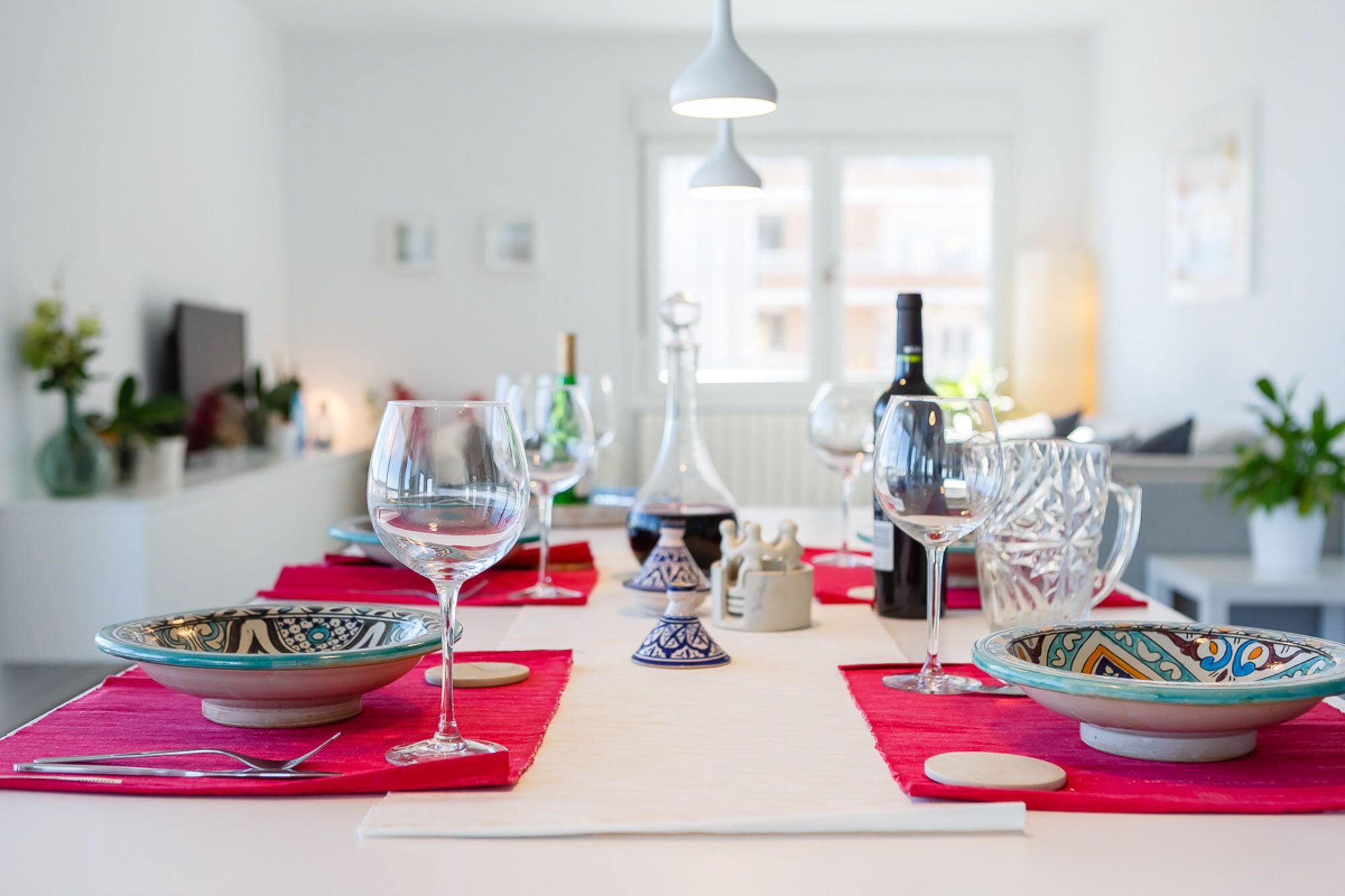 Una mesa de comedor con varias copas de vino, una botella y cuencos decorativos.