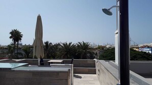 En tagterrasse med pool, udendørs møbler og udsigt over bybilledet.